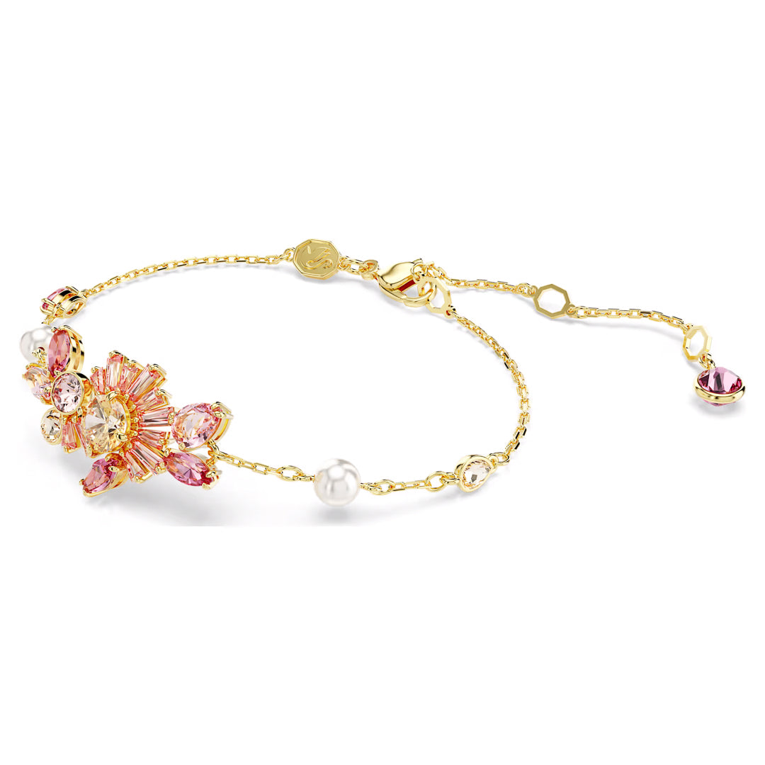 The Swarovski Gema Bracelet by Swarovski is an elegant gold accessory, showcasing a pink and crystal floral motif with pearl accents. Its adjustable chain, finished with a small round charm, embodies the sophistication of Swarovski Zirconia.