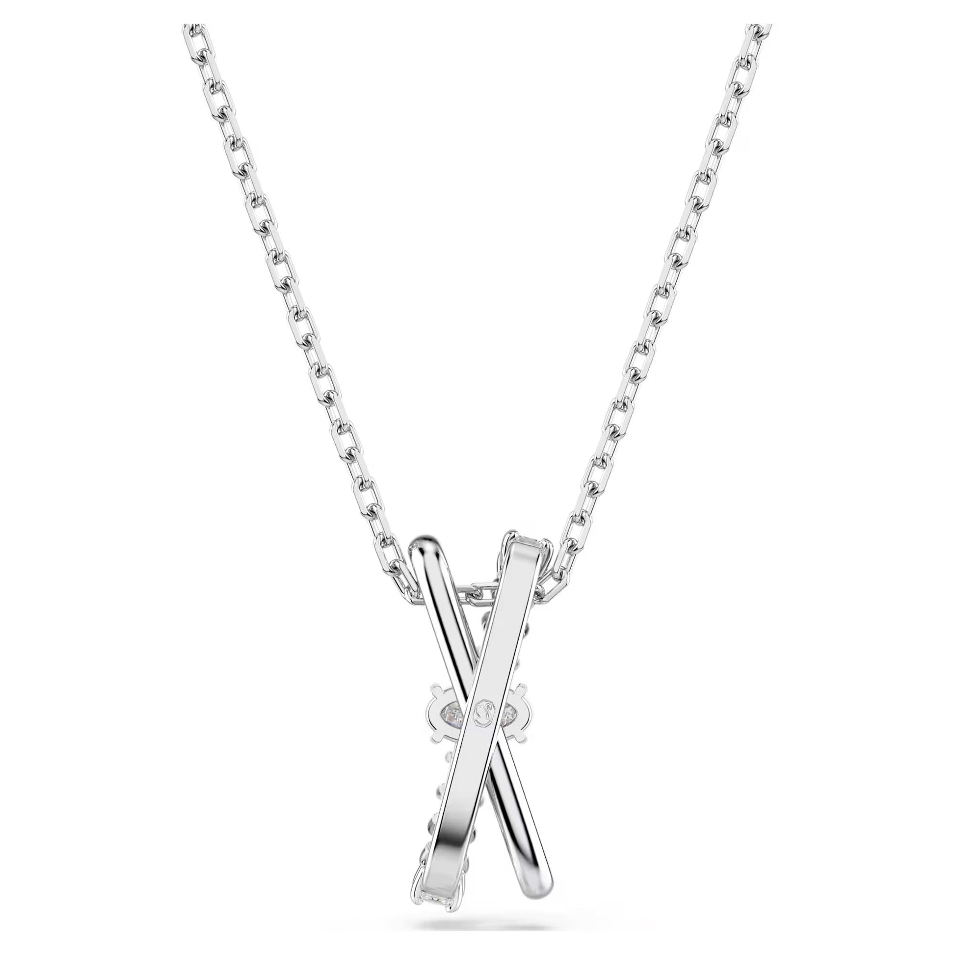 The Swarovski Hyperbola Necklace Pendant, designed by the brand Swarovski, features a rhodium-plated silver pendant with two intersecting bars forming an 'X' shape. It is displayed against a white background, with a simple link chain design and accented with a dazzling Swarovski Zirconia at the intersection.