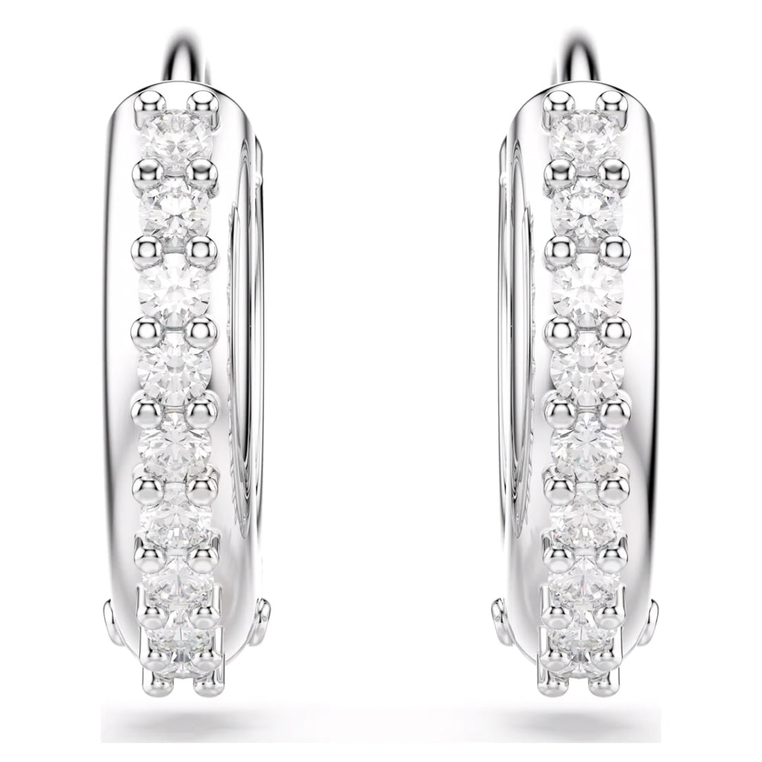 Introducing the Swarovski Matrix Hoop Earrings by Swarovski: elegant silver mini hoops that are rhodium-plated for enhanced durability. These stunning earrings feature a row of small, sparkling diamonds along the outer edge, set against a white backdrop.