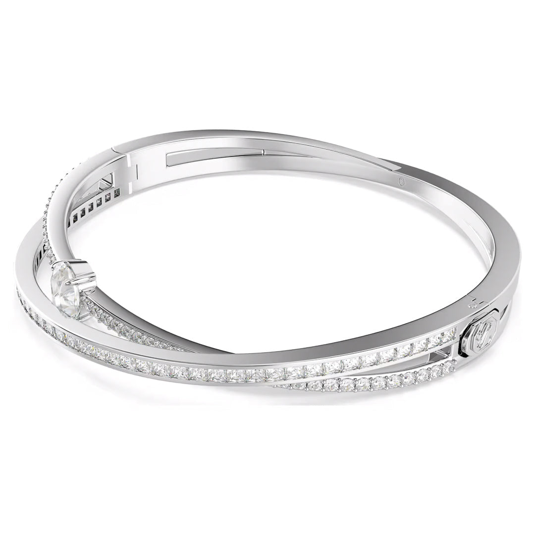 Introducing the Swarovski Hyperbola Bangle, a sophisticated silver piece featuring a distinctive overlapping design. Rhodium-plated, one band is embellished with dazzling Swarovski Zirconia stones for an elegant touch.