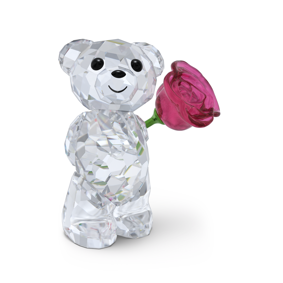 A faceted crystal teddy bear stands upright, smiling and holding a pink crystal rose in one paw against a plain white background. Inspired by the iconic Swarovski Kris Bear collection, the Swarovski Kris Bear A Rose with Love by Swarovski makes a charming Valentine’s gift.