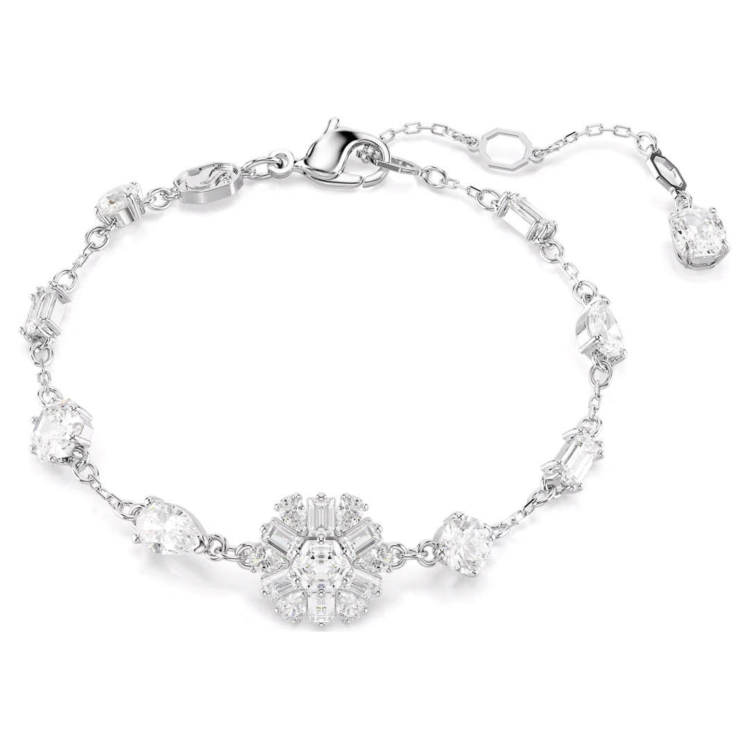 Introducing the Swarovski Idyllia Bracelet by Swarovski, a delicate silver accessory showcasing a central floral cluster adorned with shimmering Swarovski Zirconia gemstones. This rhodium-plated bracelet features a lobster clasp and an adjustable chain finished with a single gemstone.