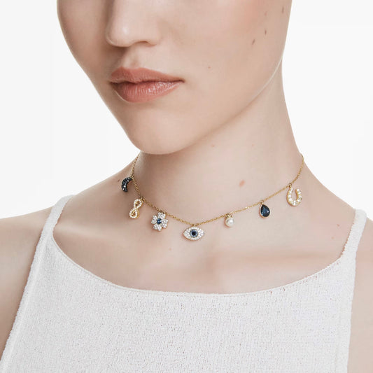 A person wearing a textured white sleeveless top adorns themselves with the Swarovski Symbolica Evil Eye Choker Necklace. This elegant gold-tone plated piece from Swarovski is decorated with delicate charms, including an eye, teardrop, horseshoe, and a Swarovski Crystal Pearl. The plain white background perfectly complements the sophisticated ensemble.