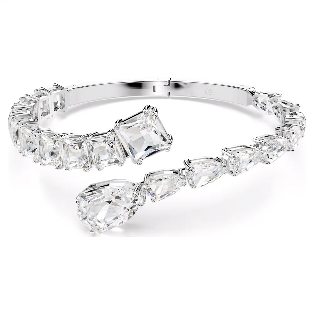 The Swarovski Matrix Cuff by Swarovski is a rhodium-plated silver bracelet adorned with large, clear teardrop and rectangular-shaped gemstones, creating a sparkling and elegant appearance.