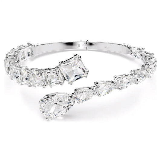 The Swarovski Matrix Cuff by Swarovski is a rhodium-plated silver bracelet adorned with large, clear teardrop and rectangular-shaped gemstones, creating a sparkling and elegant appearance.