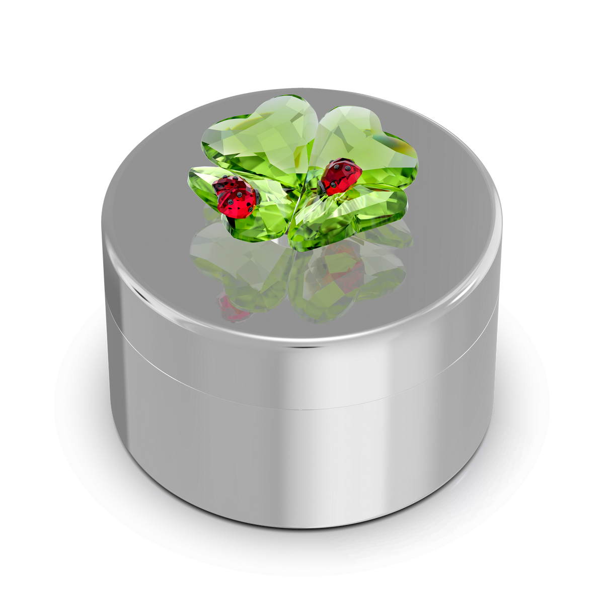 The Swarovski Idyllia Clover and Ladybug Decorative Box by Swarovski is a round silver decorative box with an ornate lid adorned with green crystal leaves and two small red ladybugs, set against a plain white background—an exquisite piece that is perfect for collectors in Swarovski Canada.