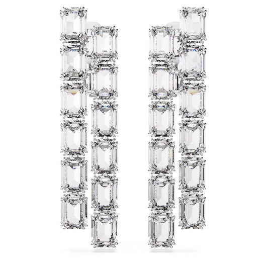 A close-up of the Swarovski Millenia Clip Earrings reveals their rectangular, multi-tiered geometric design. Enhanced by rhodium plating, these earrings showcase stunning octagon-cut crystals paired with multiple clear, emerald-cut stones arranged in vertical rows on a white background.