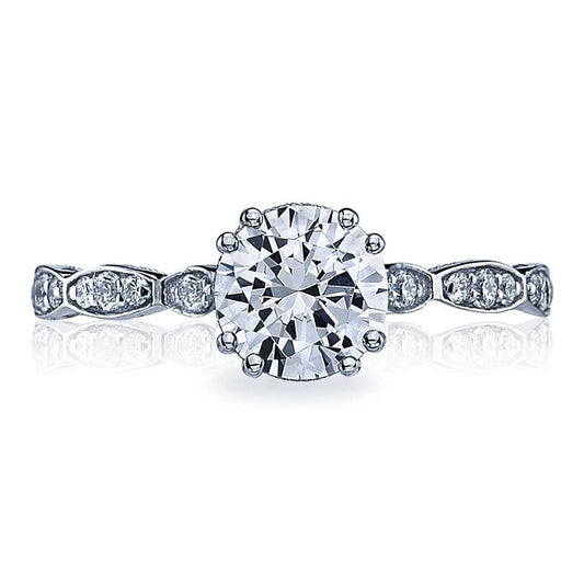 The Tacori Sculpted Crescent 18K White Gold Round Brilliant Solitaire Semi Mount with Diamond Band engagement ring features a prominent round diamond in the center, complemented by smaller diamonds embellishing the band and intricate patterns along the sides, enhancing its sophisticated and detailed design.