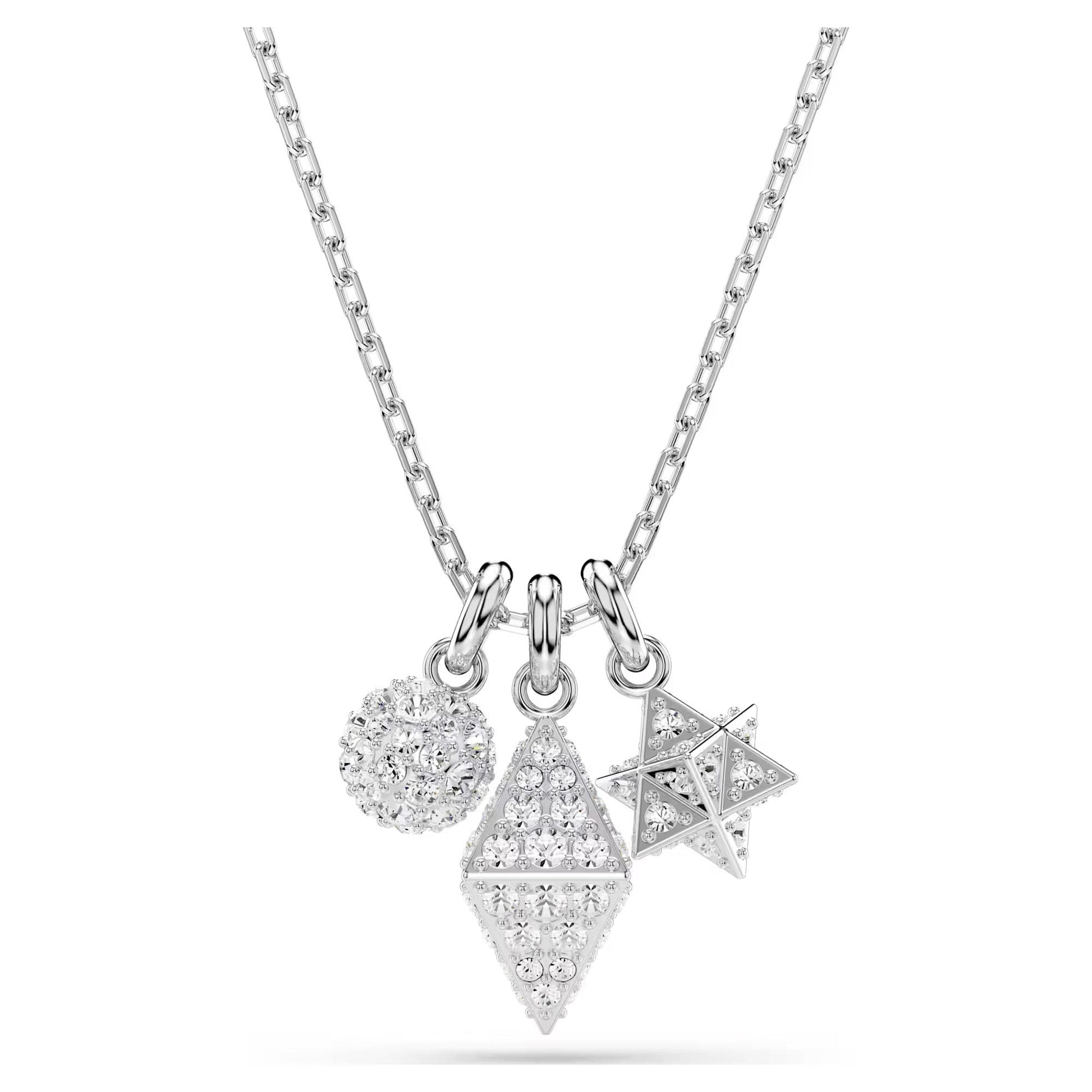Introducing the Swarovski Dextera Necklace Pendant by Swarovski—a silver necklace highlighting three geometric pendants: a round charm adorned with pavé crystals, a diamond-shaped charm decorated with embedded stones, and a starburst charm featuring a textured surface. The chain showcases a sleek silver link design.