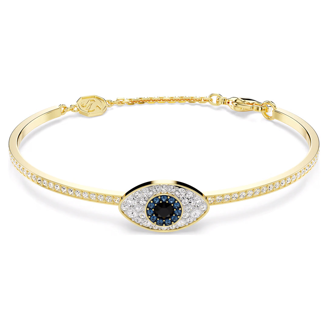 The Swarovski Symbolica Bangle by Swarovski is a gold-tone jewelry piece featuring an eye-shaped design at its center, highlighted with a dark blue stone surrounded by pavé crystals. The bracelet is adorned with small clear stones and includes a delicate closure.