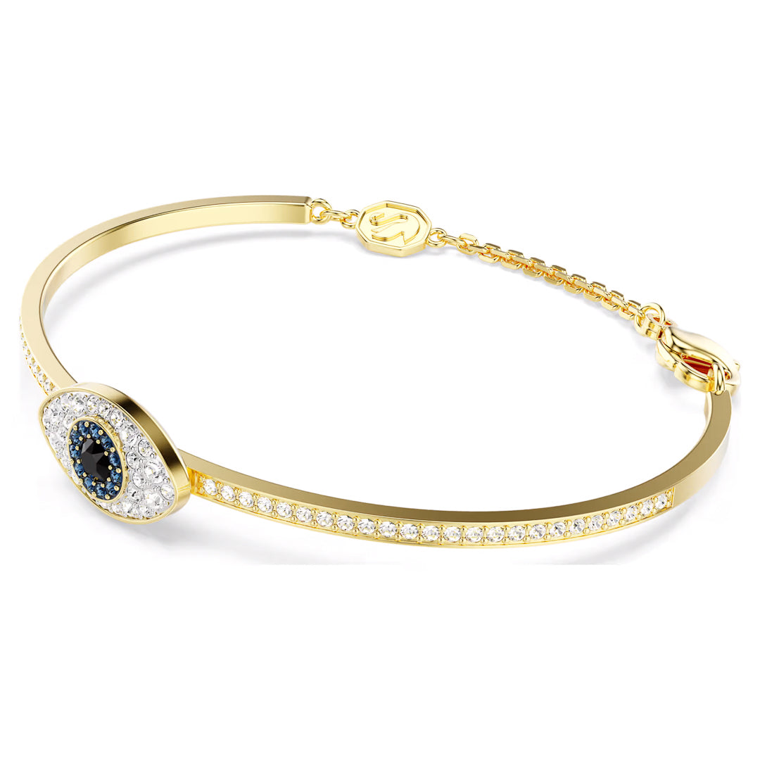 Introducing the Swarovski Symbolica Bangle, a gold-tone plated bracelet featuring a central evil eye design adorned with blue and white crystals. The band sparkles with small white crystals and features an adjustable chain embellished with a charming gold emblem clasp.