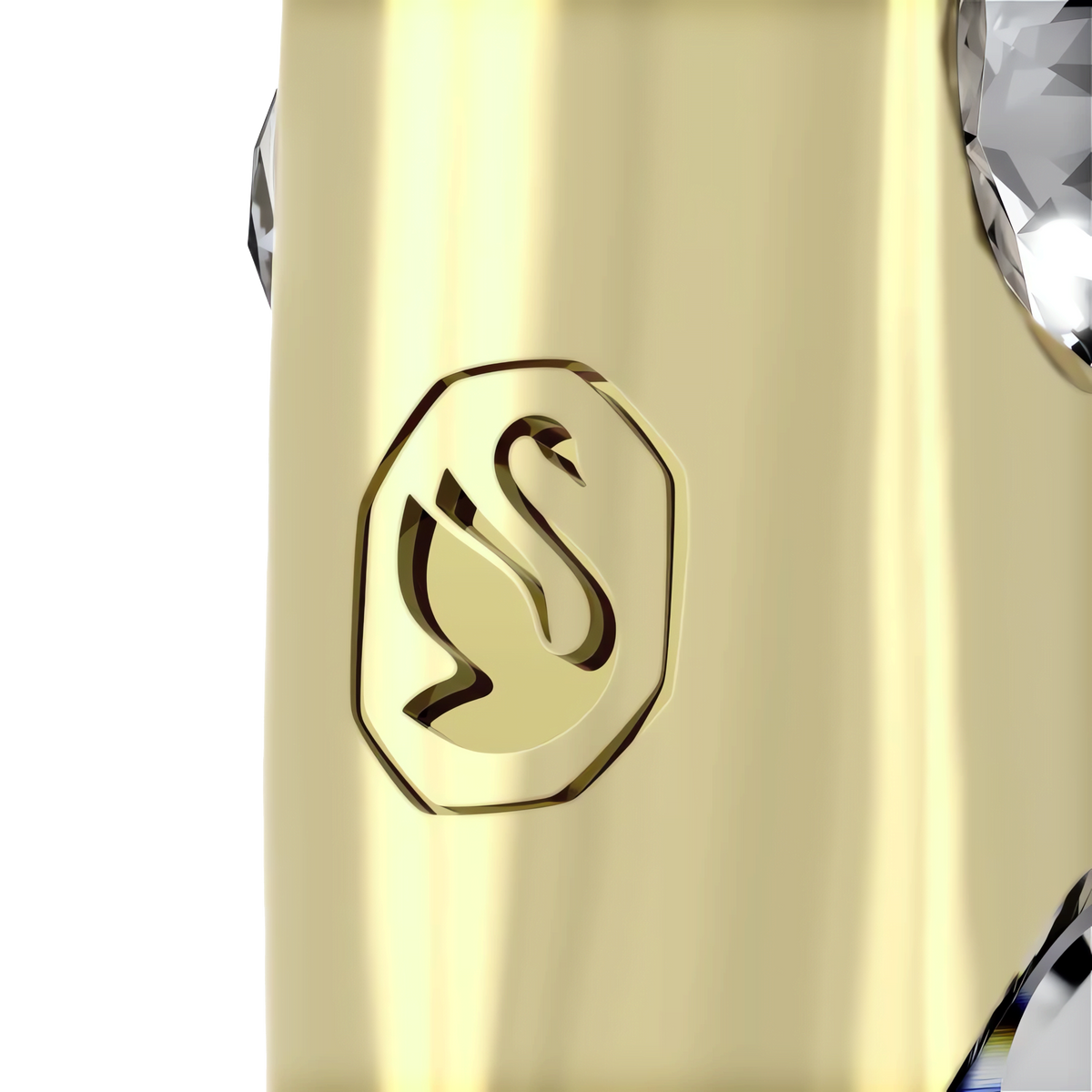 Close-up of a champagne gold-tone surface engraved with a stylized swan inside an octagonal border, next to a faceted, clear crystal element from the Swarovski Holiday Magic Music Note Ornament by Swarovski.