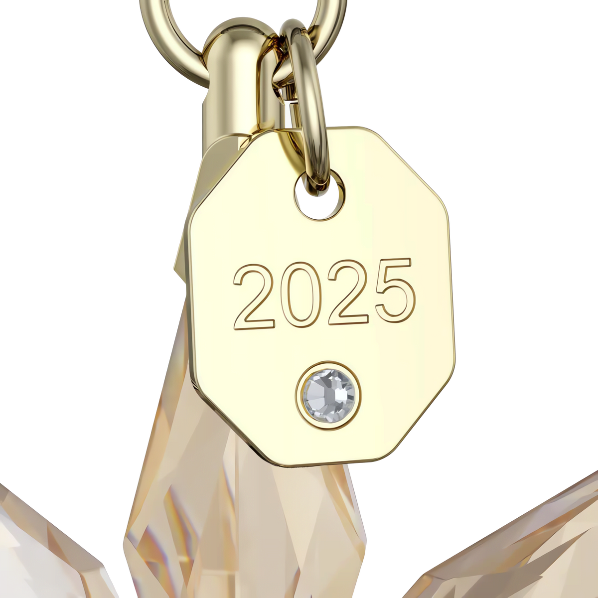 A close-up of a gold tag engraved with “2025” and a small gem below it, attached to the Swarovski Annual Edition Festive 3D Ornament 2025.