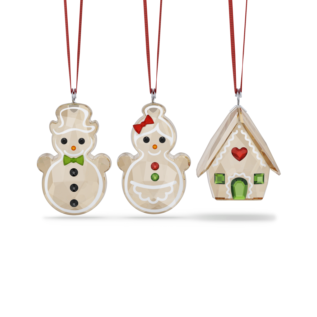 Experience the festive spirit with the Swarovski Holiday Cheers Gingerbread Ornament Set by Swarovski. This charming set includes three Christmas ornaments: two gingerbread snow people with red ribbons—one accented with a bow tie and the other with a red bow—and a gingerbread house featuring a red heart and green windows, all elegantly displayed against a white background. An ideal holiday gift, these delightful ornaments add sparkle to your tree and pair beautifully with other sparkling Swarovski décor.