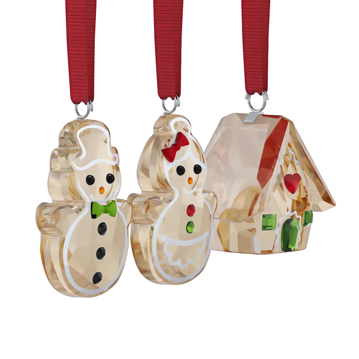 The Swarovski Holiday Cheers Gingerbread Ornament Set by Swarovski features three elegant crystal ornaments with red ribbons: two gingerbread snowpeople—one adorned with a green bowtie, the other with a red bow—and a beautifully decorated gingerbread house accented with a heart and delightful details, making it the perfect holiday gift.
