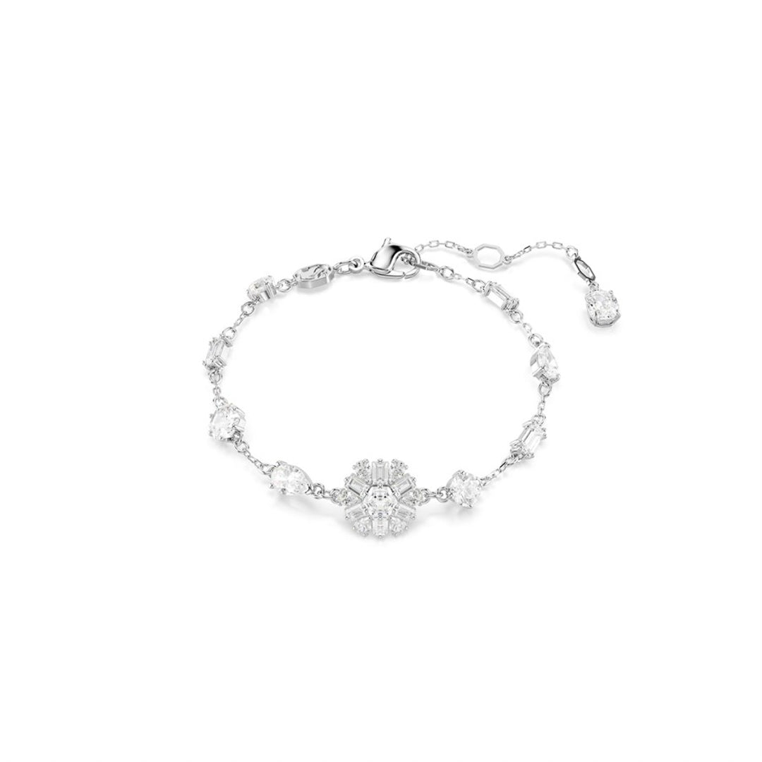 The Swaroavski Idyllia Bracelet by Swarovski is an elegant silver piece with a central floral motif adorned with sparkling white crystals, complemented by an adjustable, rhodium-plated band.