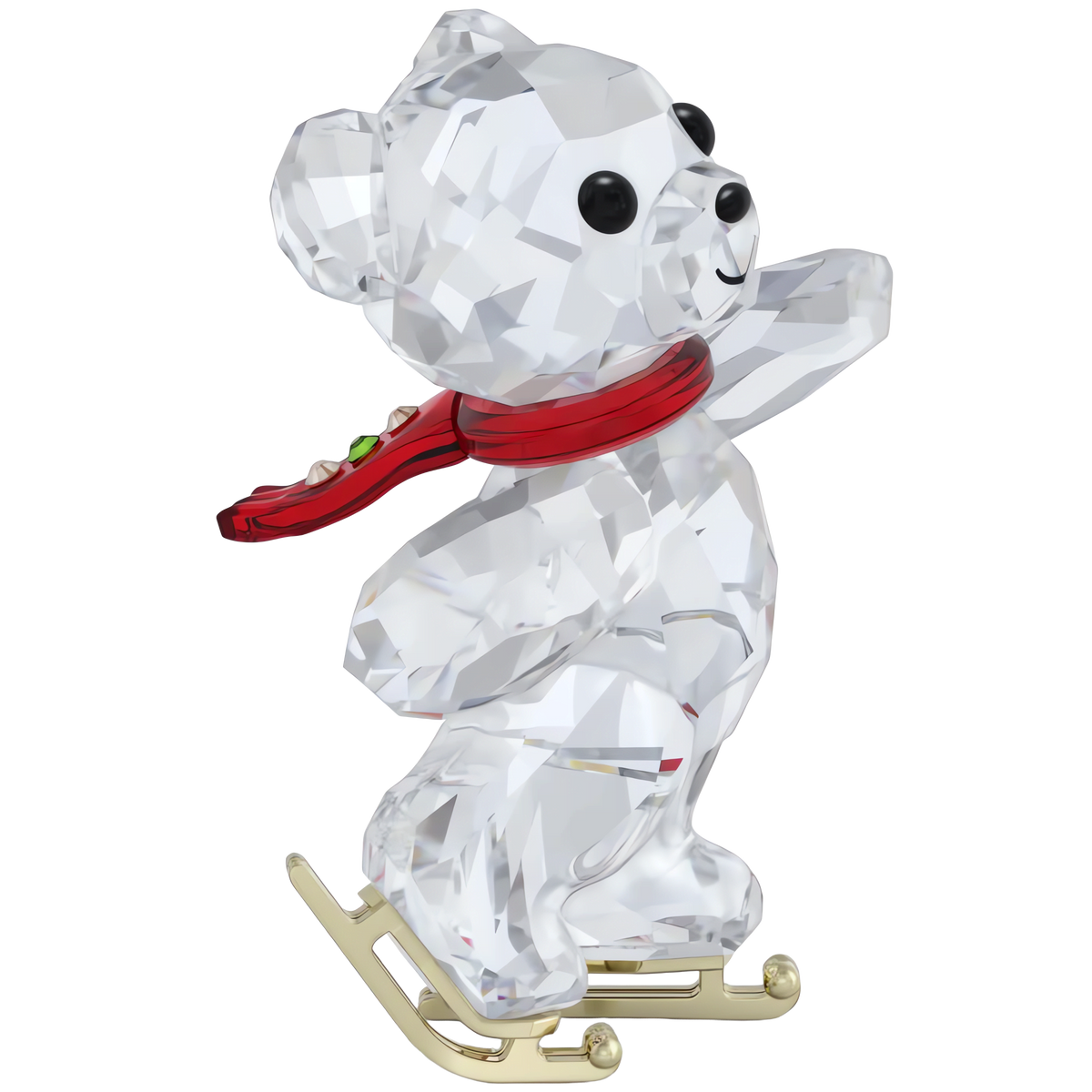 The Swarovski Kris Bear 130th Anniversary figurine from Swarovski, available at Raffi Jewellers, features a faceted crystal bear ice skating on gold-colored skates while wearing a red scarf, gazing upward with one arm raised against a white background.