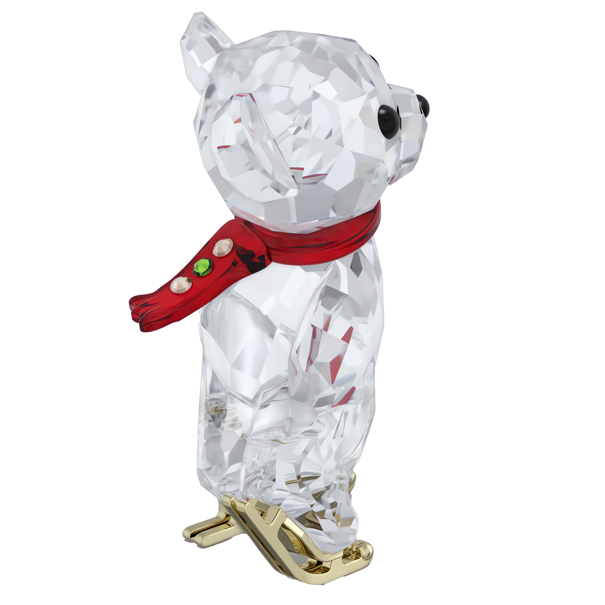 A Swarovski Kris Bear 130th Anniversary figurine from Swarovski, offered by Raffi Jewellers, is depicted in profile facing right on a plain white background, wearing a red scarf with green accents and gold ice skates.