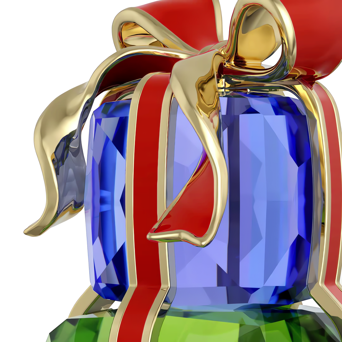 A close-up of the Swarovski Holiday Cheers Gifts by Swarovski, featuring a shiny blue faceted gem wrapped with a gold and red metallic ribbon like a festive decoration, sitting atop a green faceted gem, set against a plain white background.