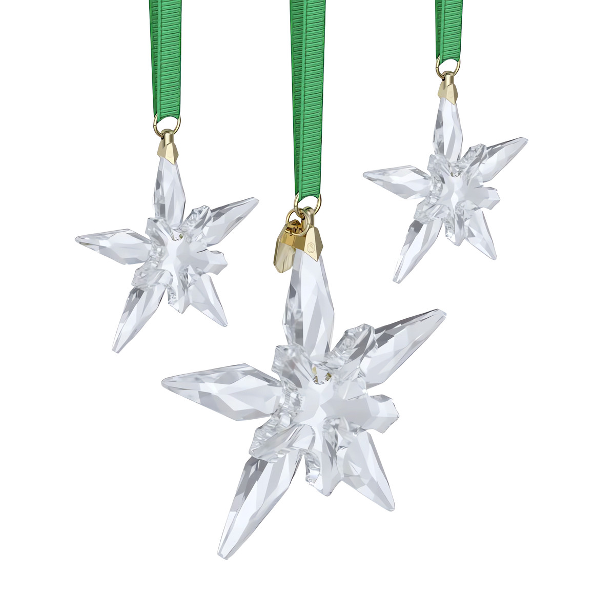 Three crystal star ornaments with gold tops hang from green ribbons against a white background, capturing the elegance of the Swarovski Annual Edition Ornament Set 2025. Discover this sparkling set from Swarovski, available through an authorized retailer in Canada.