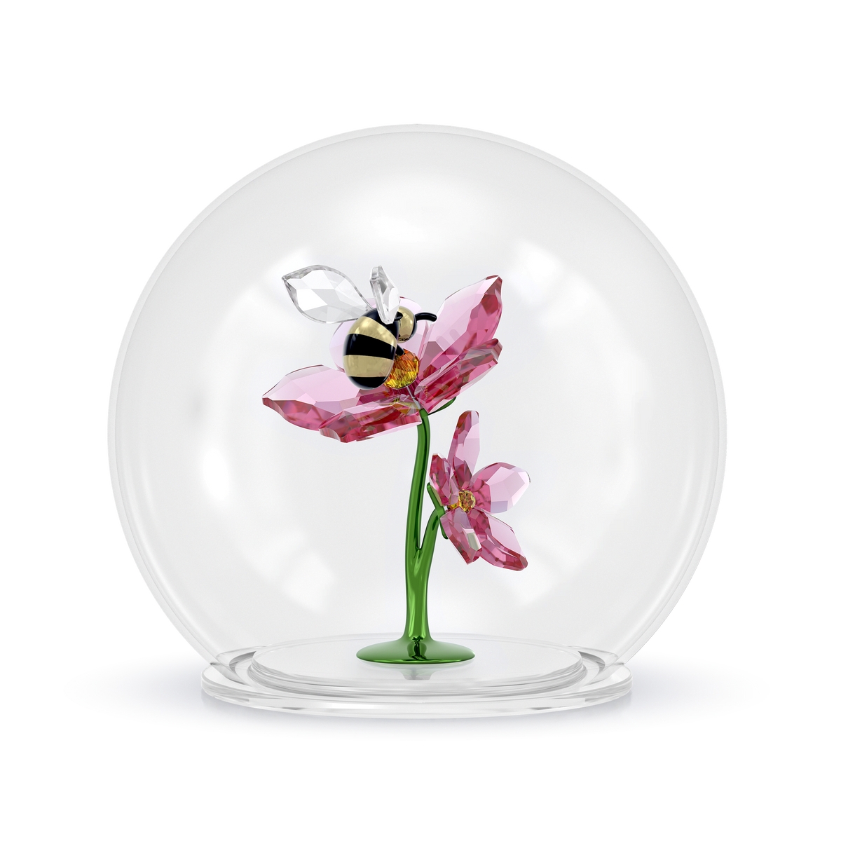 The Swarovski Idyllia Glass Ball Bee and Flowers by Swarovski features a glass dome encasing a crystal bee figurine delicately perched on a pink flower with green stem and leaves, all presented on a clear round base—an exquisite floral decoration for any collection.