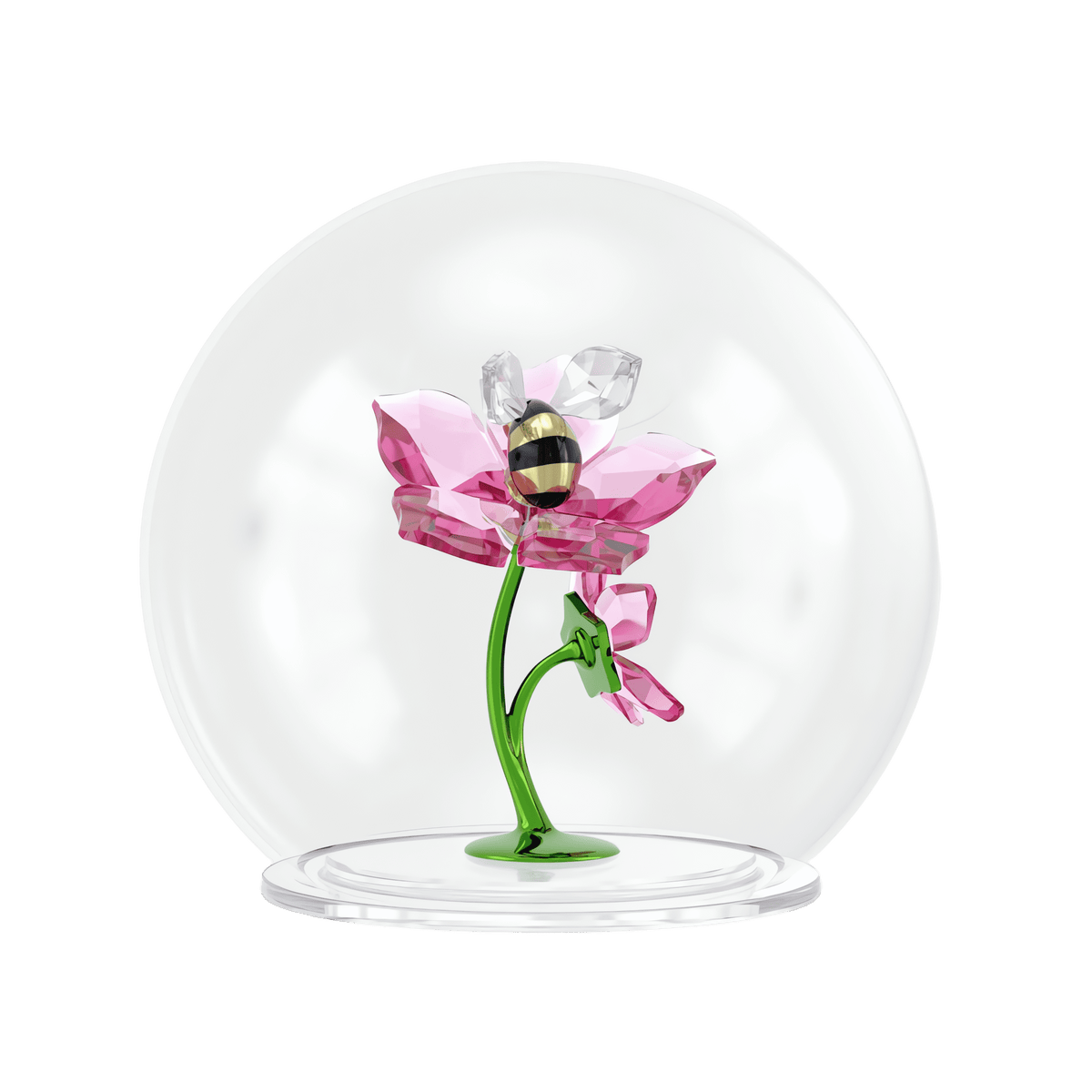 Encased within a glass dome, the Swarovski Idyllia Glass Ball Bee and Flowers by Swarovski features a delicate pink crystal flower with a green stem, accented by a shimmering Swarovski crystal bee figurine perched on one of its petals, all set against a plain white background.