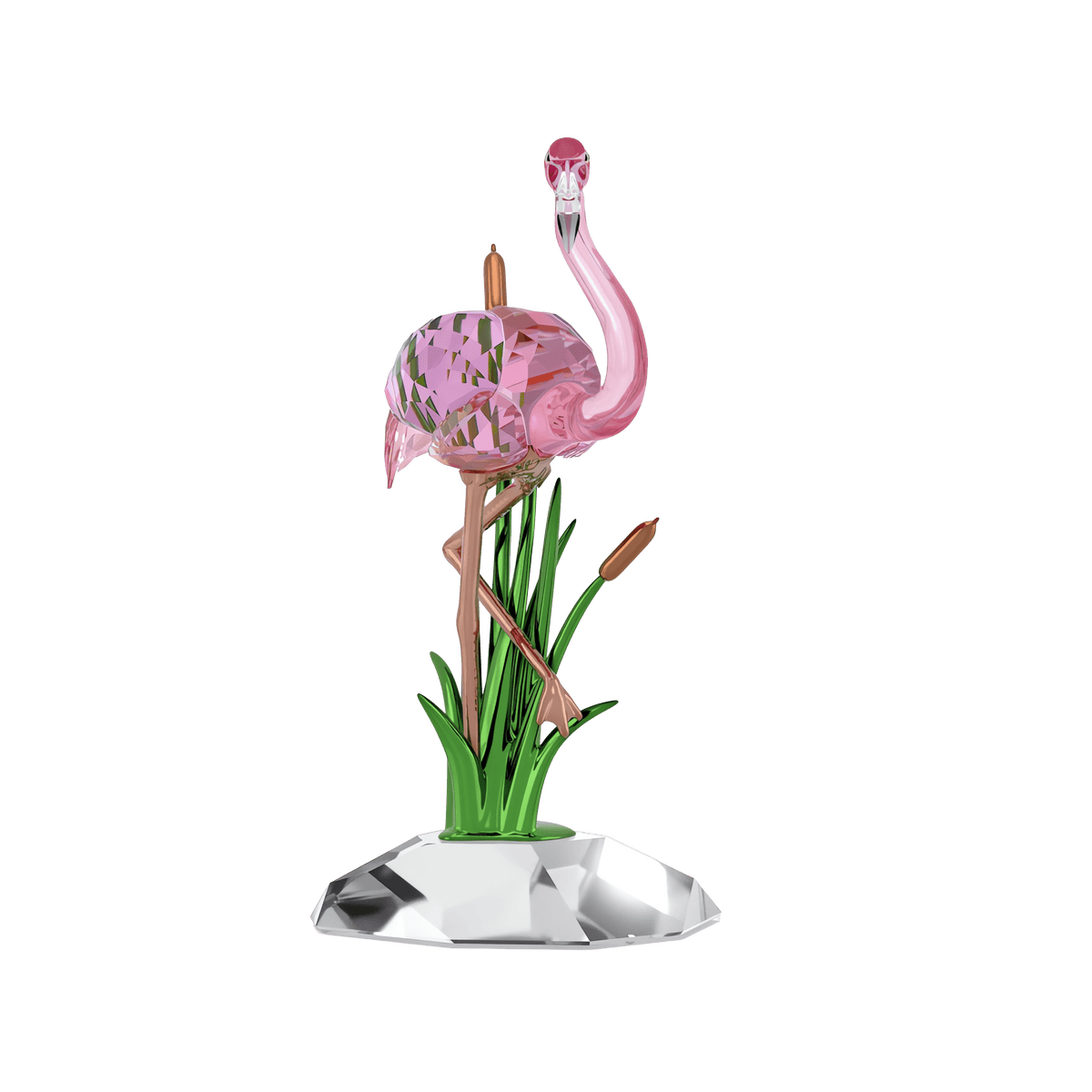 The Swarovski Idyllia Flamingo by Swarovski features a pink glass flamingo balanced on one leg among green glass reeds and brown cattails, all displayed on a faceted clear base, creating a striking decorative piece against a plain white background.