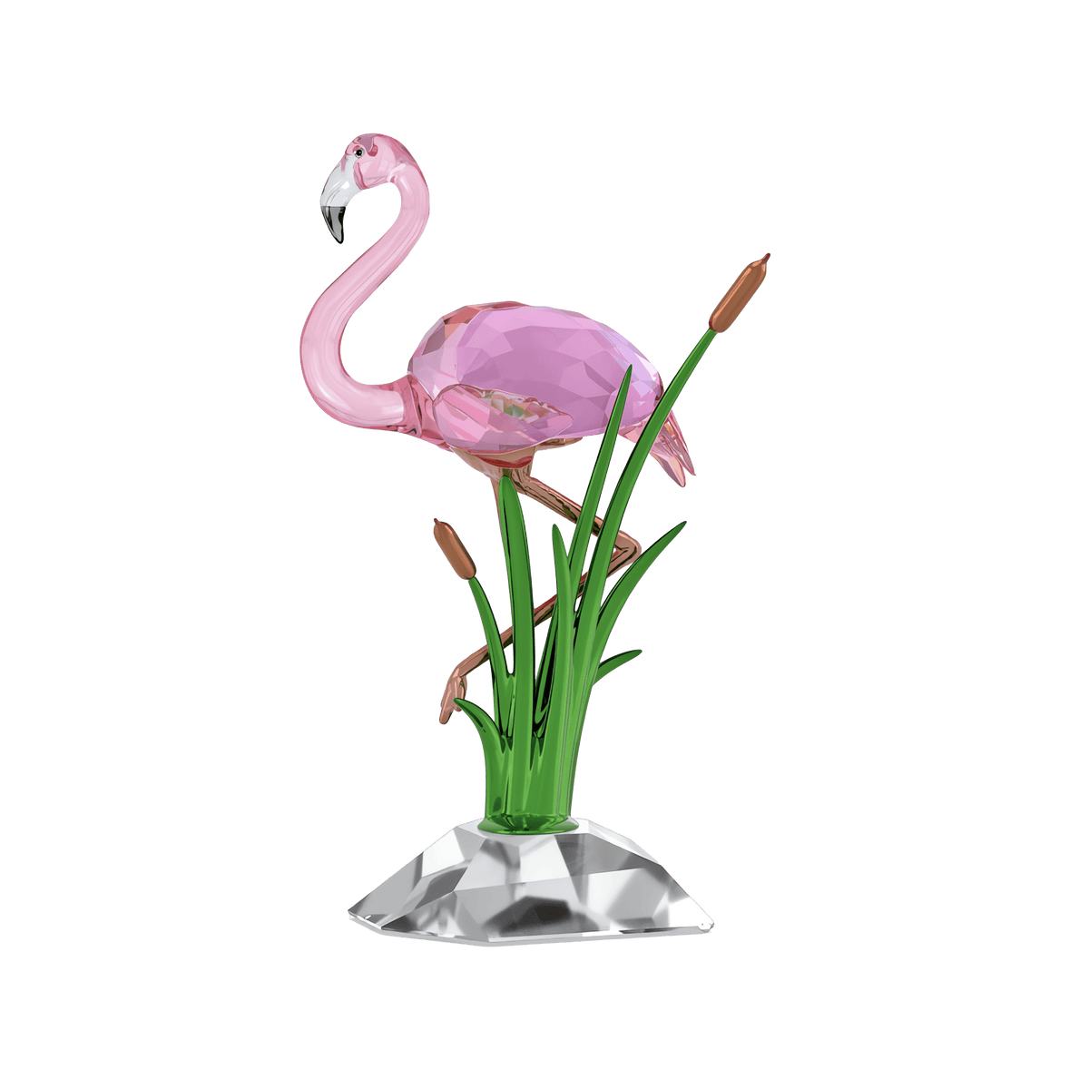 The Swarovski Idyllia Flamingo by Swarovski is a pink glass flamingo figurine standing on a faceted clear base, accented by green glass reeds and brown cattails, creating a charming decorative accent against a white background.