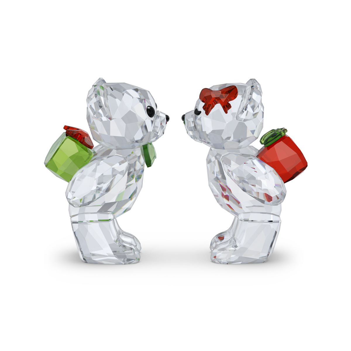 The Swarovski Kris Bear Holiday Annual Edition 2026 features two crystal teddy bears facing each other, each with a sparkling, faceted surface and holding a gift box behind their back—one green and one red. One bear is adorned with a red bow on its head, making this Swarovski collectible the perfect addition to any display or collection of exquisite crystal figurines.