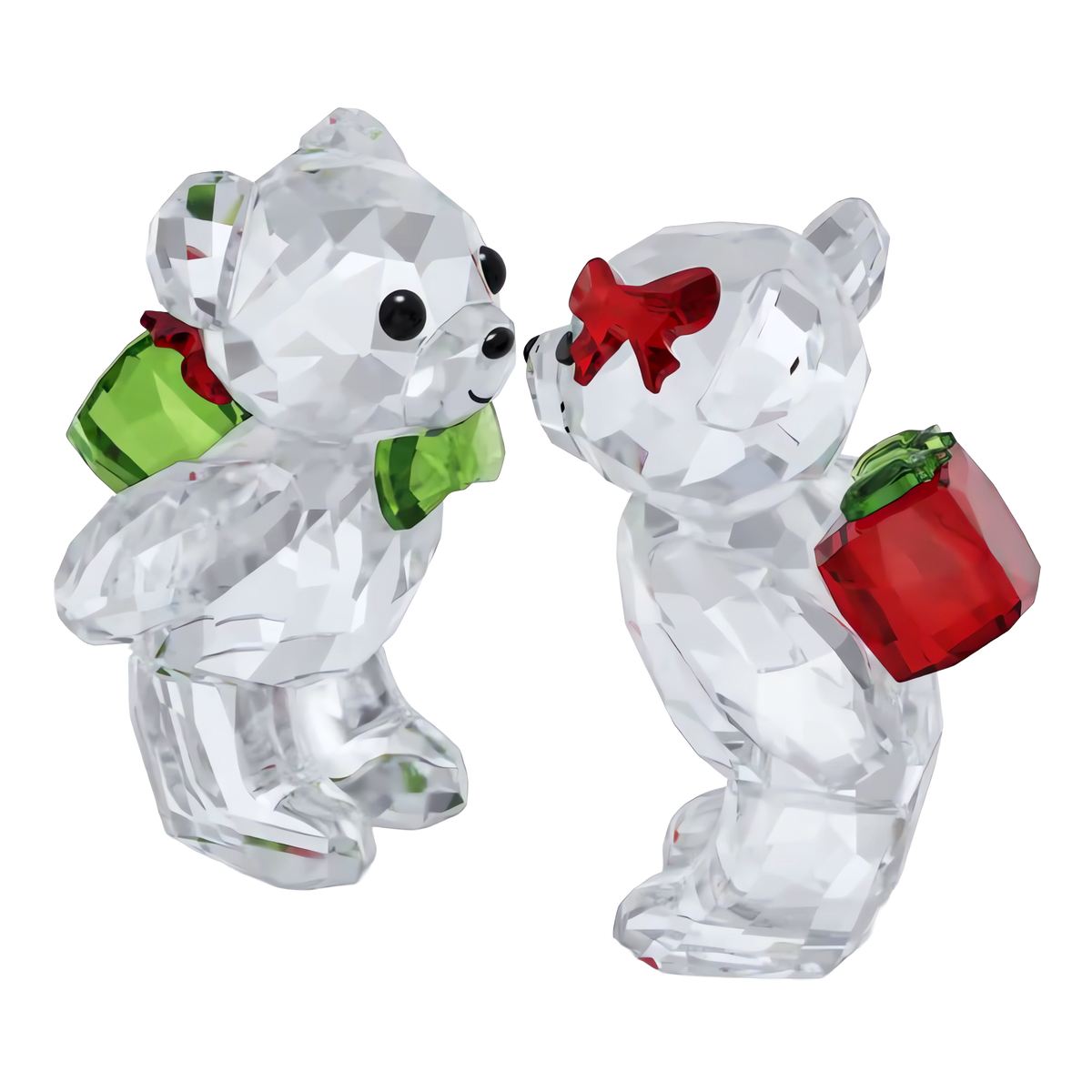 Two Swarovski Kris Bear Holiday Annual Edition 2026 figurines face each other in this charming Swarovski display. One crystal bear features a green bow tie and holds a green gift, while the other wears a red bow on its ear and holds a red gift. Both figurines are expertly crafted from clear, faceted crystal.