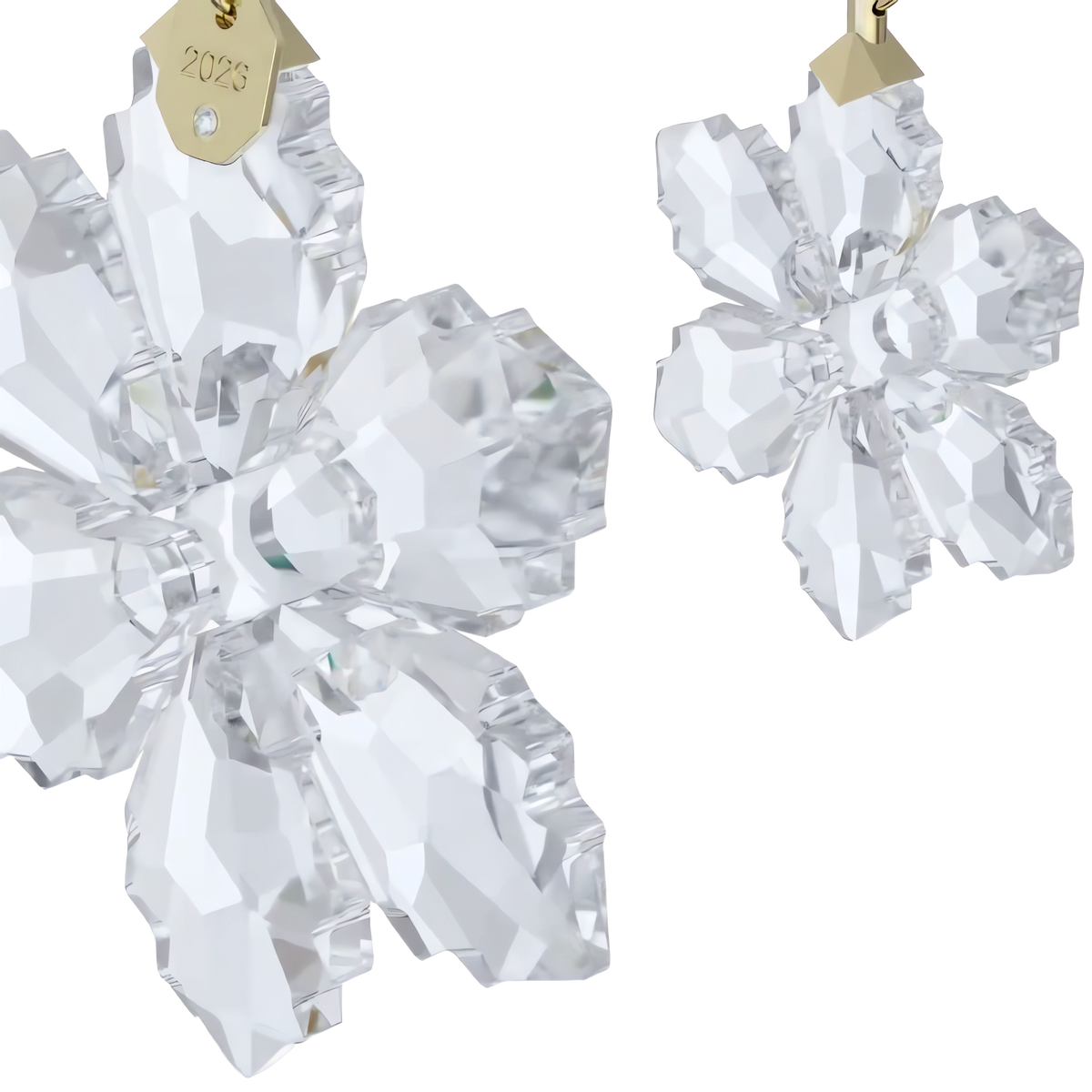 Introducing the Swarovski Annual Edition Ornament Set 2026: two hanging crystal flower ornaments adorned with gold tags engraved “2026.” This limited-edition holiday decoration by Swarovski showcases clear, multifaceted crystals that create a stunning sparkle against any backdrop.