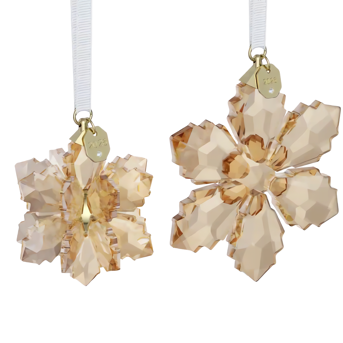The Swarovski Annual Edition Festive 3D Ornament Set 2026 by Swarovski features two gold-colored crystal snowflake ornaments with faceted surfaces that hang from white ribbons, each adorned with a small gold tag. This elegant set beautifully captures the brilliance of the renowned Festive Annual Edition Ornament against a plain white background.