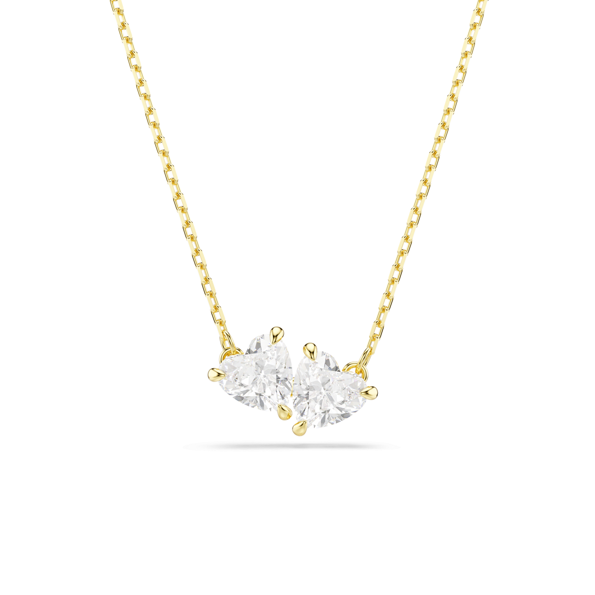 A Swarovski Mesmera necklace with heart-shaped white Swarovski Zirconia, crafted in an 18K gold finish, is displayed in a minimalist style against a plain white background.