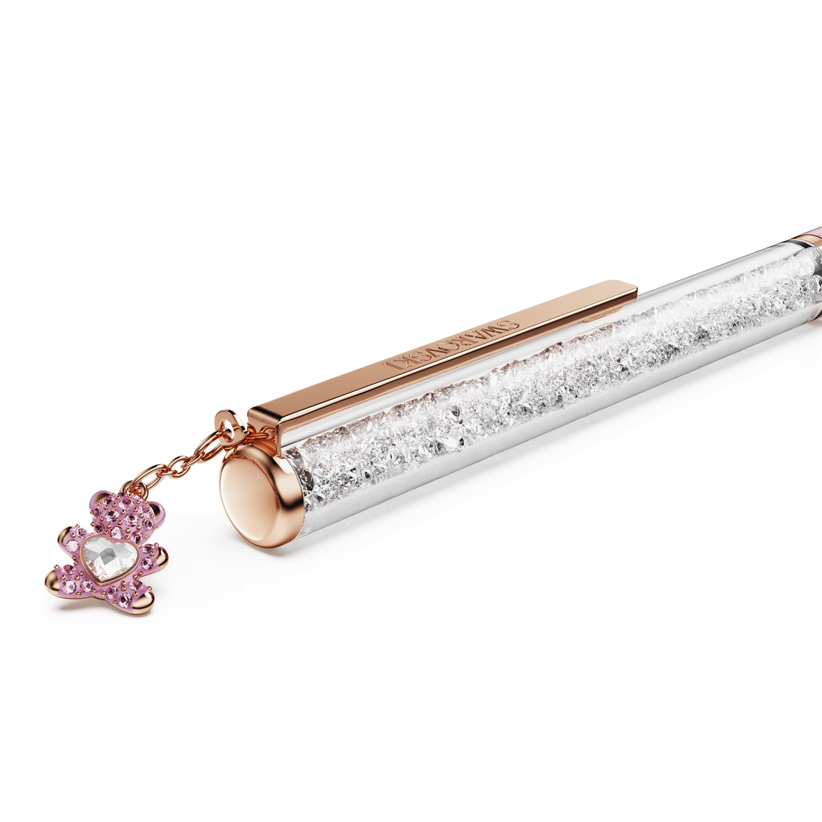 The Swarovski Crystalline ballpoint pen, Teddy in Pink, features a sleek design with rose gold-tone plating, a clear barrel filled with sparkling crystals evoking signature Swarovski brilliance, and is adorned with a pink lacquered teddy bear charm attached to the clip.