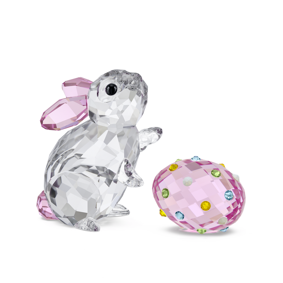 The Swarovski Idyllia Rabbit and Egg by Swarovski features a charming crystal rabbit with delicate pink ears and tail next to a pink crystal egg adorned with colorful gems, set against a plain white background—a delightful collectible offered by Raffi Jewellers, an authorized retailer of Swarovski Canada.
