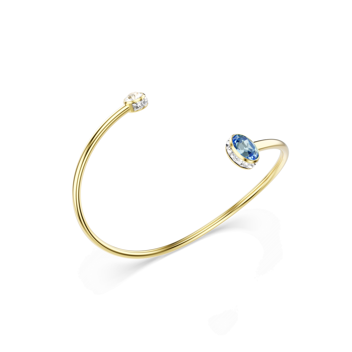 The Swarovski Chroma bangle by Swarovski features a sleek 18K gold finish and an open design, showcasing a round clear Swarovski Zirconia on one end and an oval blue gemstone on the other, displayed against a white background.