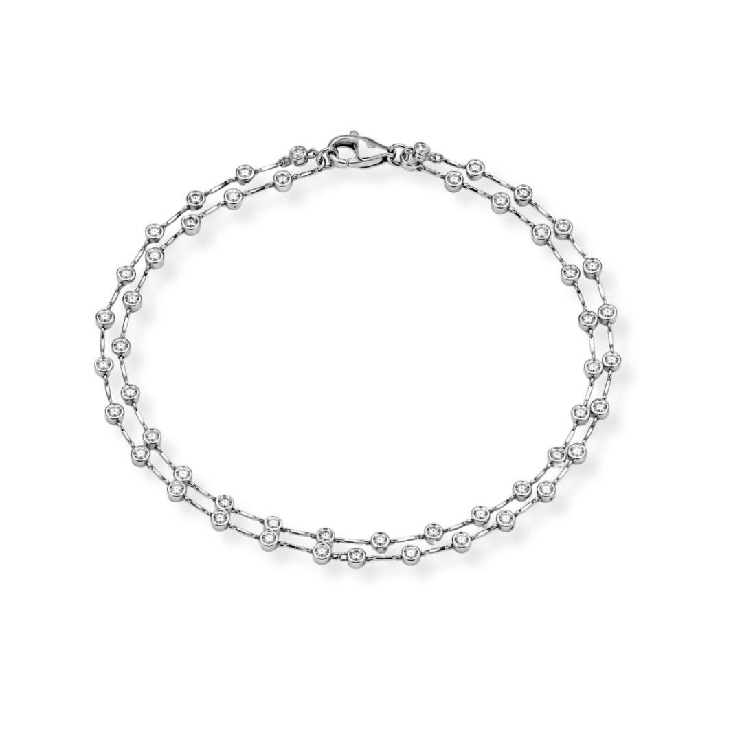 A refined Raffi&Co.® 18K White Gold Diamond Station Necklace, showcasing evenly spaced round brilliant diamond stations along a delicate white gold chain, elegantly presented in a circular arrangement against a plain white background.