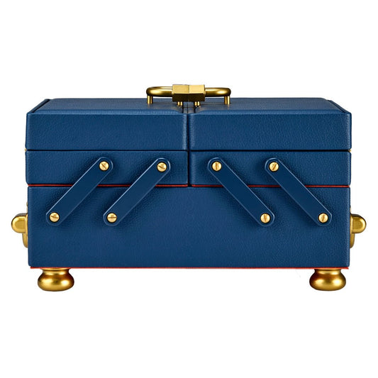 The WOLF 1834 Marla Aaron Baby Everything Jewellery Box is a rectangular blue vegan leather box with gold feet and handle, four diagonal decorative straps with gold rivets on the front, a textured surface, and orange trim at the base.