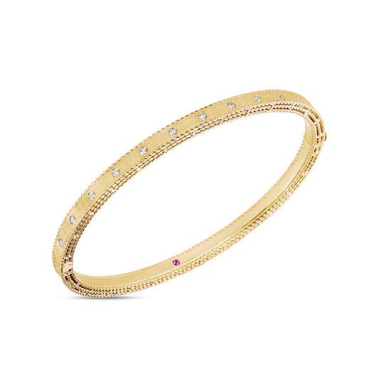 The Roberto Coin 18K Yellow Gold Princess Diamond Satin Bangle is a refined piece featuring intricate detailing around its surface, complemented by small diamonds.