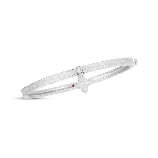 This Roberto Coin Princess Flower Symphony Bangle is a delicate satin bracelet in silver, showcasing intricate detailing and a captivating diamond flower charm with a red gemstone at its center, crafted in 18k white gold.