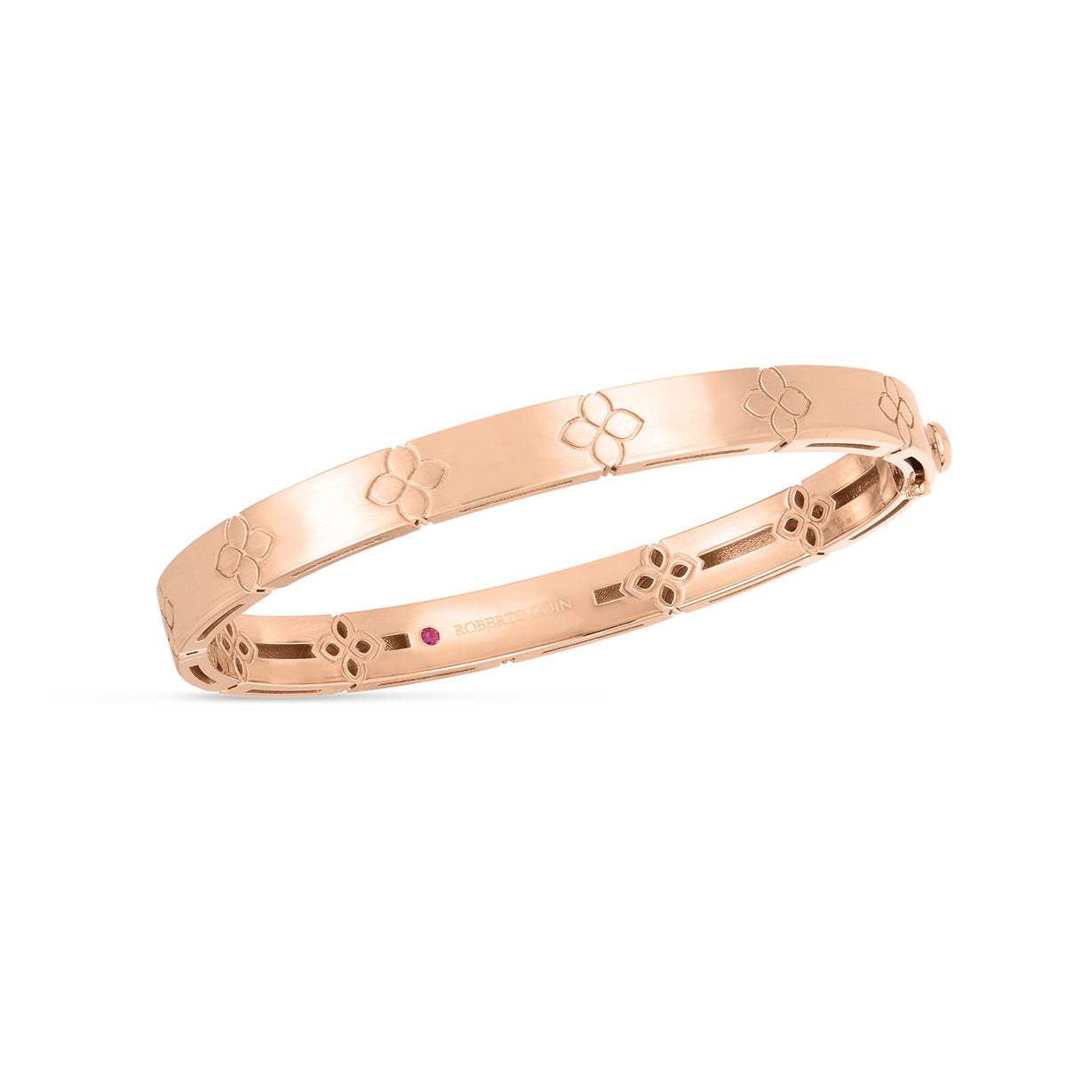 Introducing the Roberto Coin Love In Verona 18K Rose Gold Medium Width Bangle, an exquisite piece from Roberto Coin that showcases a delicate floral motif adorning its surface. This bangle is crafted in stunning 18K rose gold and features a smooth, polished finish with a subtle shine. Additionally, it includes an elegantly set small red gemstone inside.