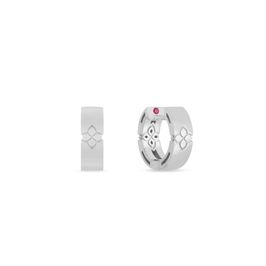 A pair of 18K white gold earrings with intricate geometric designs beautifully embody the elegance of Roberto Coin's Love In Verona collection. The earring on the right features a small red gemstone, adding to its allure. Both earrings are displayed against a plain white background.