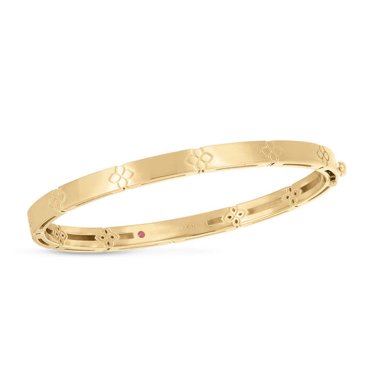 The Roberto Coin Love In Verona 18K Yellow Gold Narrow Bangle showcases a delicate floral pattern along its surface. Its polished finish enhances its elegance and simplicity, making it the perfect accessory to pair with a dainty pendant chain for a complete look.