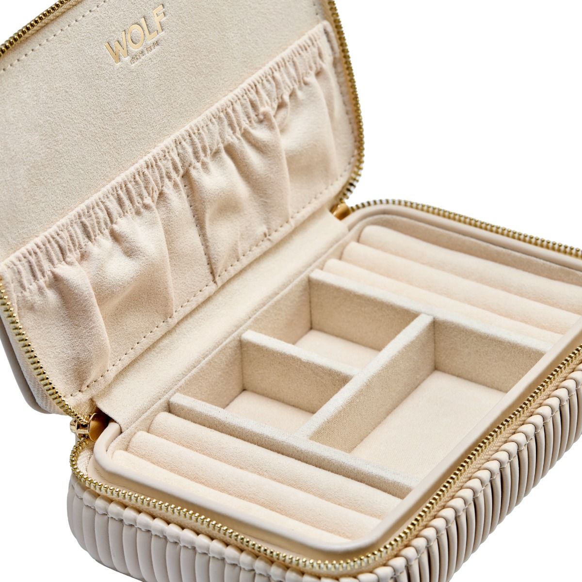 The WOLF 1834 Bella Zip Jewellery Case is a beige travel organizer with zip closure, padded compartments, ring slots, soft fabric lining, elasticized lid pockets, and gold-embossed "WOLF" branding inside.