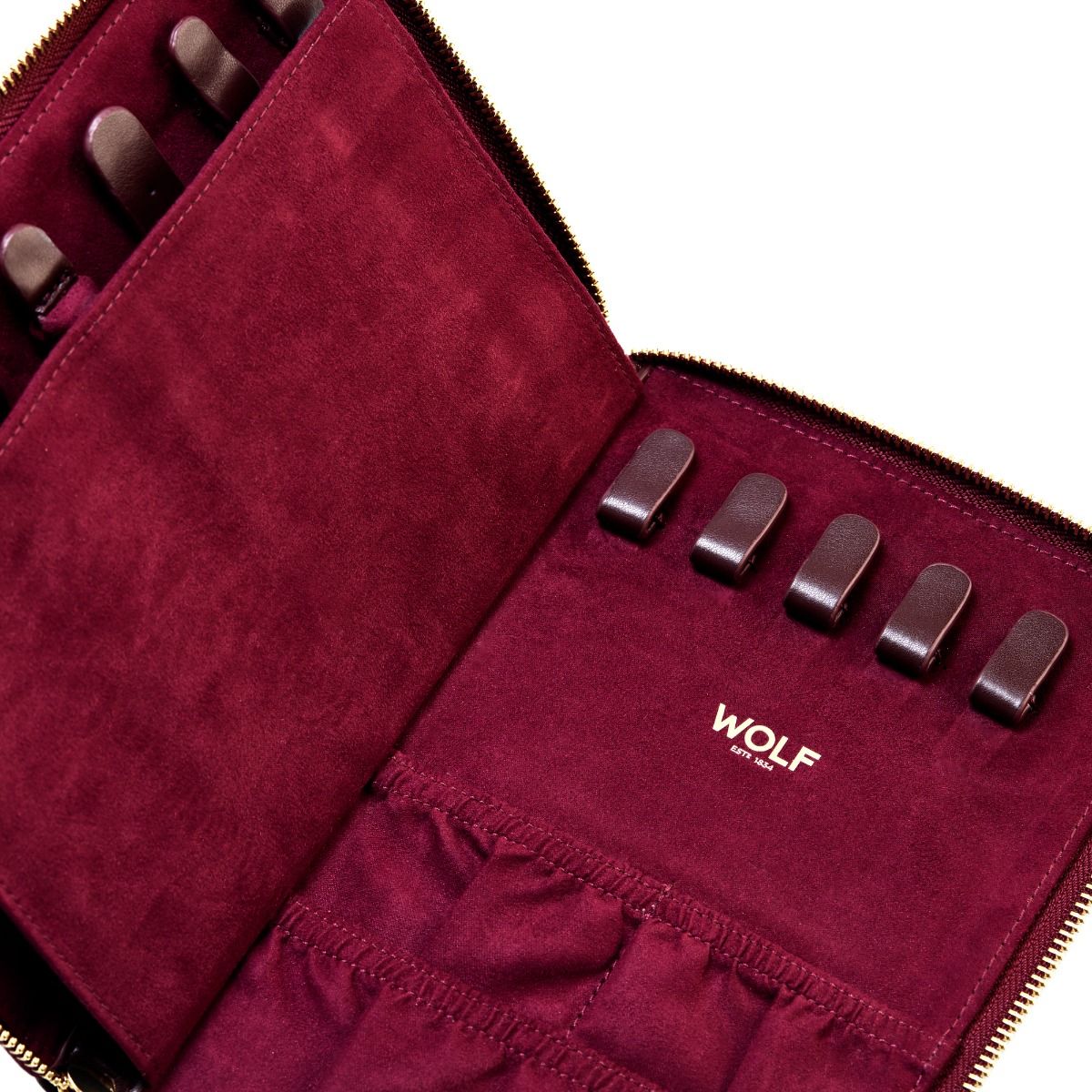 The WOLF 1834 Bella Jewellery Portfolio is a maroon suede zippered case with six slots and elastic pockets, lined with soft LusterLoc to protect jewelry. "WOLF 1834" is stamped inside, making it an elegant travel organizer.