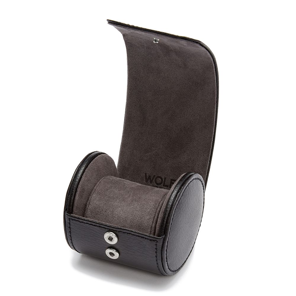 The WOLF 1834 British Racing Single Watch Roll by WOLF is a black vegan leather travel case with a soft gray suede interior, featuring a cylindrical cushion for one watch and snap buttons on the front of the flipped-back lid.
