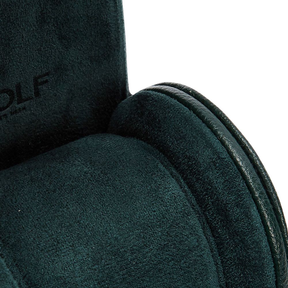 Close-up of the WOLF 1834 British Racing Single Watch Roll in dark green vegan leather with curved shapes and textured surface; partial "WOLF" branding is visible, emphasizing its compact, elegant design.