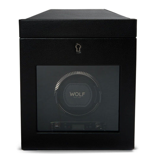 The WOLF 1834 British Racing Watch Winder With Storage features a single slot with rotation options, showcased through its glass front. The interior proudly displays the brand name "WOLF," while the exterior is adorned with a leather-like texture. A keyhole located at the top center secures its lock-in dynamic cuff feature.