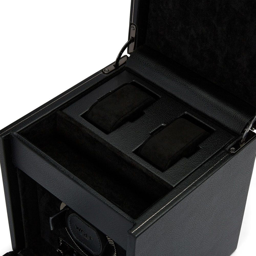Unveil the WOLF 1834 British Racing Double Watch Winder With Storage. This elegant black leather case, lined with velvet, securely holds two wristwatches. It includes rotation settings and a motorized mechanism at the base, functioning as a watch winder. Inside, the patented dynamic lock-in cuff guarantees secure placement of your watches against a plain white backdrop.