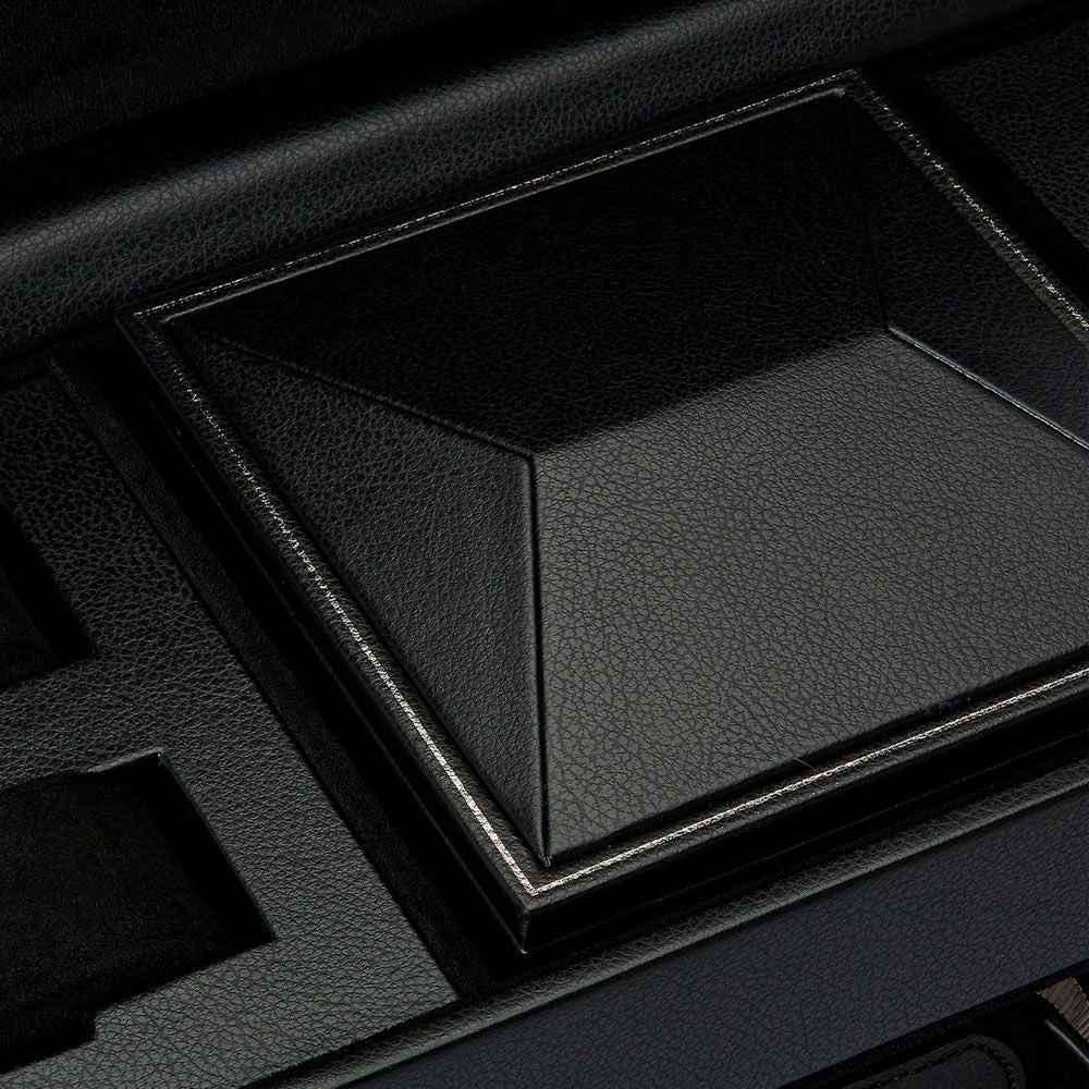 Close-up of the textured black leather lid of the WOLF 1834 British Racing Triple Watch Winder With Storage. This lid, with its raised pyramid-like design and patented lock-in feature, is surrounded by other interior compartments of the case, making it perfect for securing your watches.